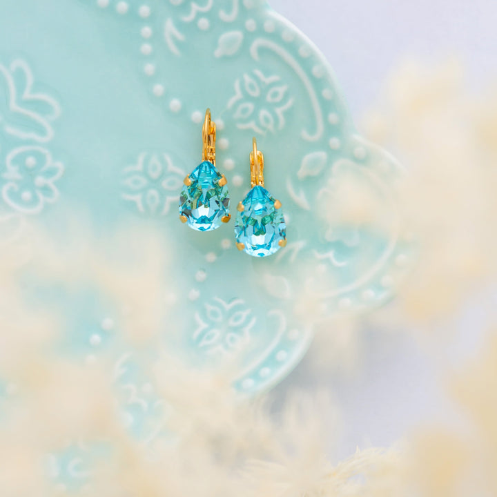 A pair of Adele Aqua Blue Earrings on a blue plate